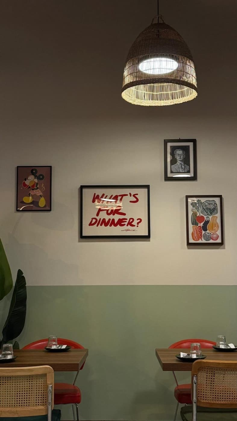 Framed prints, including a red 'What's for dinner?' artwork, on the sage-green dining room wall