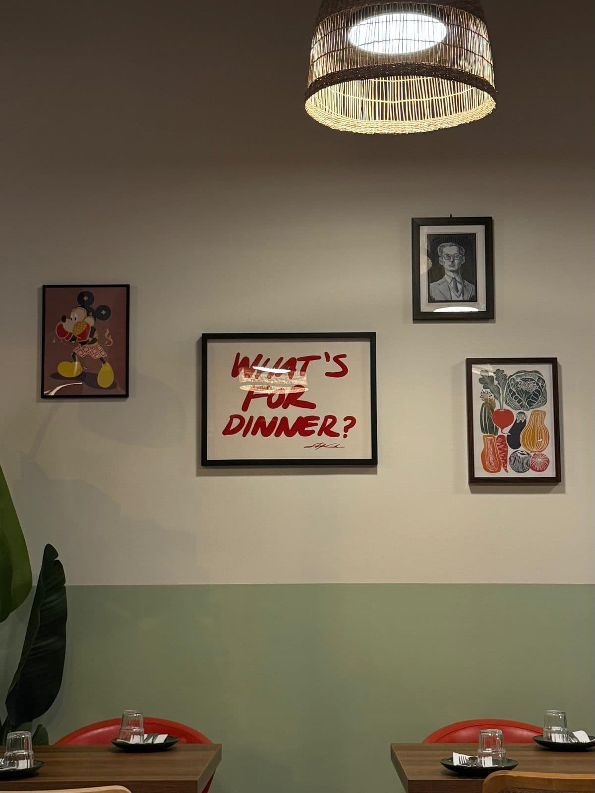 Warm dining room wall with framed art and a glowing pendant light
